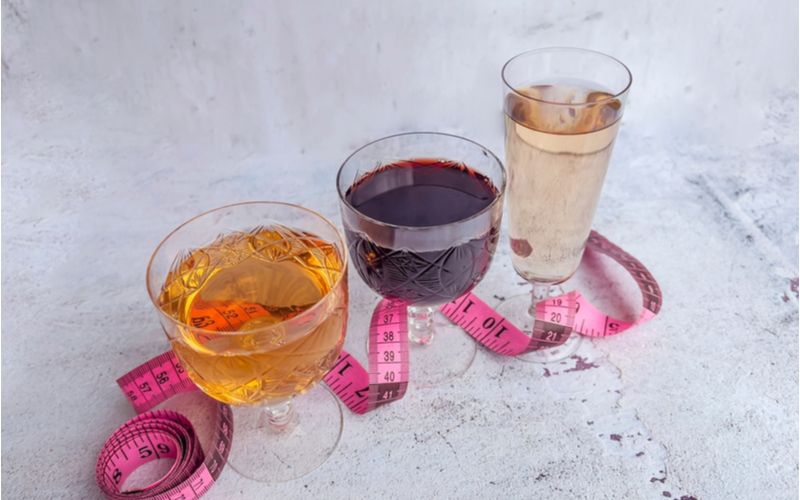 Prázdné kalorie alkohol - sklenice s vínem, krejčovský metru