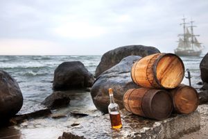 Investiční rum - sudy a láhev rumu na skalnatém pobřeží