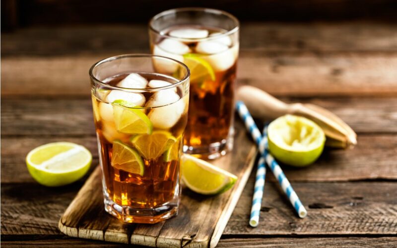 Drink Long Island Iced Tea ve skleniccích, brčka a citrony vedle