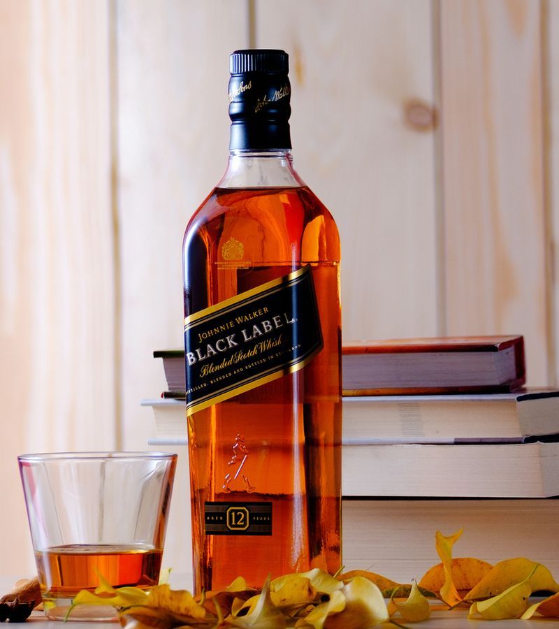 Johnnie Walker Black Label - láhev a sklenička s whisky na stole