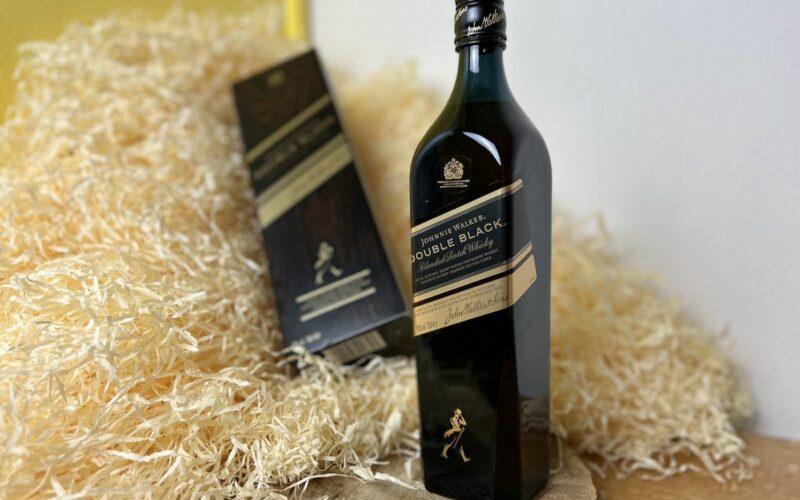 Johnnie Walker Double Black - celá láhev na dřevěném podnosu a v pozadí karton