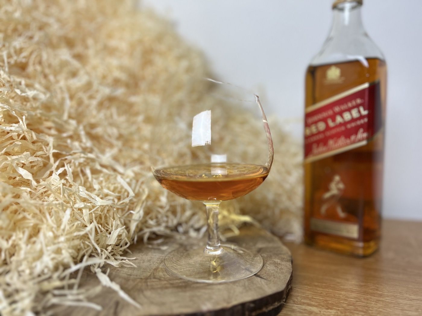 Johnnie Walker Red Label - sklenice s alkoholem na dřevěném podnosu