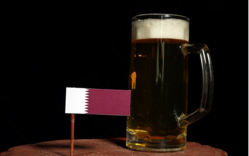 MS ve fotbale Katar a pivo - katarská vlajka a sklenice piva na dřevěné podložce