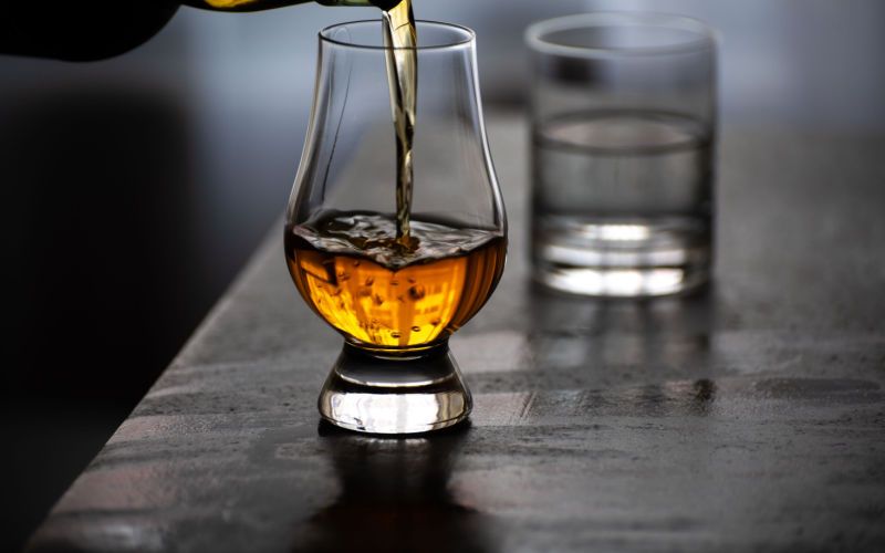 Nejlepší whisky - skotská, irská, bourbon: nalévání whisky do degustační sklenice ve tvaru tulipánu