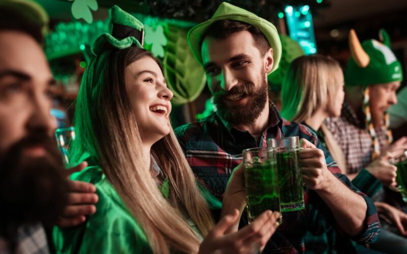 Den svatého Patrika na zeleno - tři muži a dvě ženy v typických zelených kloboucích as pivem v ruce při oslavě St. Patricks Day