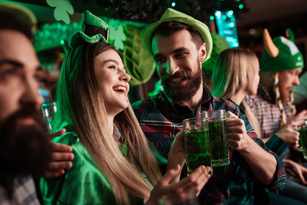 Den svatého Patrika na zeleno - tři muži a dvě ženy v typických zelených kloboucích as pivem v ruce při oslavě St. Patricks Day