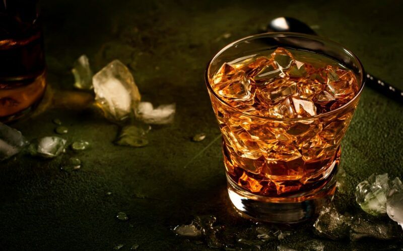 Godfather koktejl se skotskou whisky, likérem amaretto a ledem - na barovém pultu