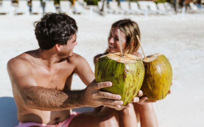 Kokosová voda, kokosové ořechy s brčkem na pláži někde v Latinské Americe